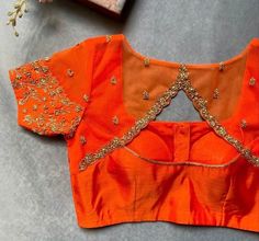 Hand embroidered ready made saree blouse / crop top/stitched saree blouse usa / orange round neck  saree blouse/ hand embroidered blouse/zardosi blouse/U neck  saree blouse/ orange pure silk blouse/ maggam work blouse        It is very true that a perfect blouse is the one which makes your saree look stand out !! If you find one of such a style that you have been wanting to have then dont let it go !! we carry such unique trending blouses that instantly add a stylish look to any saree !!     Well..!! we understand that you may not get in your desired size/pattern, here you go with customization according to your size/pattern which we can deliver in 1-2 weeks of time period !!      Here is a beautiful Hand embroidered saree blouse in orange color that has simple yet unique embroidery on nec Round Neck Saree Blouse, Zardosi Blouse, Embroidery Blouse Saree, Hand Embroidery Blouse, Latest Blouse Neck Designs, Green Blouse Designs, Ready Made Blouse, Modern Blouse, Maggam Blouse