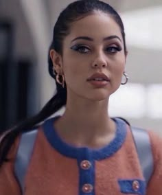 a woman in an orange and blue dress with her hair pulled up into a ponytail