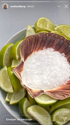 a bowl filled with sugar and limes on top of a table next to a cell phone