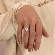 a close up of a person's hand with a diamond ring on their finger