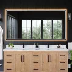 a bathroom vanity with two sinks and a large mirror above it, in front of a black wall