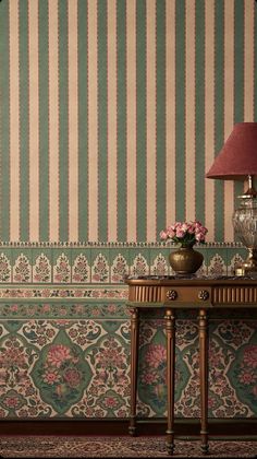 a table with a lamp on top of it next to a wallpapered wall