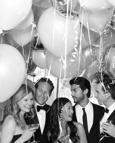 a group of people standing next to each other in front of balloons