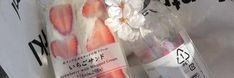 a bottle with strawberries and flowers on it sitting next to a white flower in a plastic bag