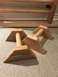 three wooden toys sitting on the floor in front of a door and stairs with carpet