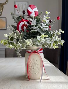 a vase filled with flowers and candy canes on top of a table in front of a window