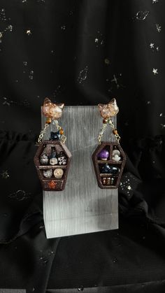 Witchcraft Whimsy Collection  Dive into the enchanting world of my Curiosity Cabinet earrings. 🗝️ Unlock the mystery within each coffin shape, revealing miniature treasures like bottles, a skull, and crystals. The cat head bead, suspended by chains, adds an extra layer of joy. These earrings are a captivating addition to the Curiosity Cabinet collection. Are you ready to explore the unknown?    Original Designed Handmade Earrings.  If you don't have your ears pierced please leave the note for changing to Earclips. (no extra charge)   - Measurements: total length 6cm - Materials: Polymer clay, Crytal Bead, Resin, 18k gold plate wire, Balsa Wood. - Weight: Approx. 3.9g/each earring. Super Lightweight!!  *Follow us on Instagram: Instagram.com/lovelinessstudio_ *Visit our website for 10% off Witchy Earrings, Ears Pierced, Curiosity Cabinet, Coffin Shape, Earrings Polymer Clay, Gothic Jewelry, Polymer Clay Earrings, Handmade Earrings, Clay Earrings