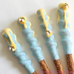 four decorated candy sticks in the shape of jellyfishs with yellow and blue icing