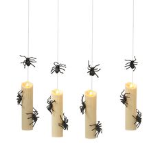 four candles with black spider decorations hanging from the top and one candle in between them