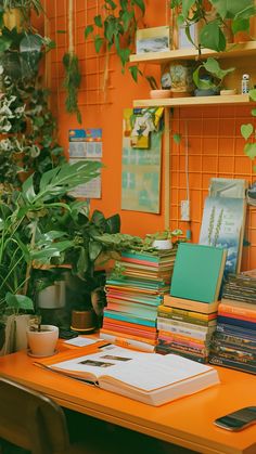 an orange desk topped with lots of books next to a potted plant and phone