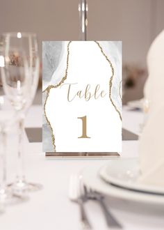 a place card with the number one on it is sitting next to some wine glasses