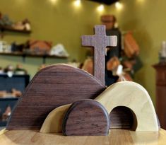 a wooden cross sitting on top of a table next to a piece of wood in the shape of a snail