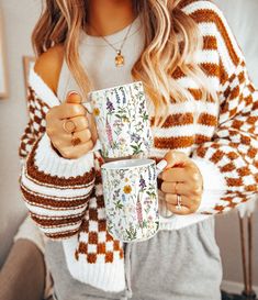 a woman holding two coffee mugs in her hands