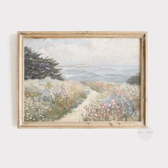 a painting hanging on the wall next to a wooden frame with flowers and trees in it