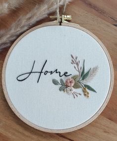 a hand embroidered hoop with the word home on it