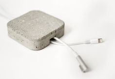 an electronic device is plugged in to a concrete block with two white wires attached