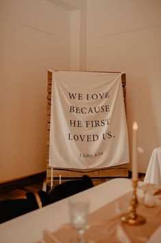 a white banner that says we love because he first loved us with candles on the table