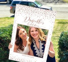 two women are posing for a picture in front of some bushes with their name on it