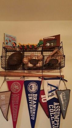 several pennants hanging from a wall with sports related items in the basket on top