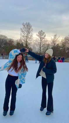 two girls standing in the snow with one pointing at something while the other holds her hand out