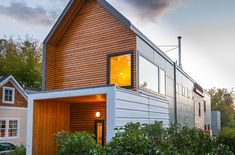 a house with wooden siding and windows on the outside, surrounded by greenery at sunset