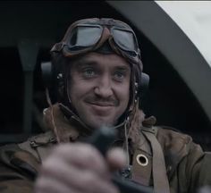 a man in an air force pilot's helmet holding a remote control to the camera