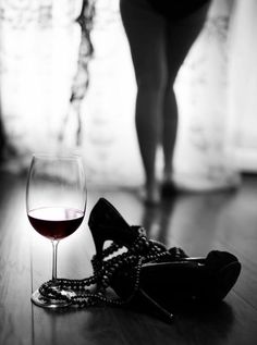 a glass of wine sitting on the floor next to a woman's shoe and chain