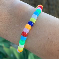 a person's arm with a bracelet made out of multicolored plastic beads