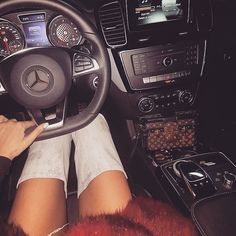 a woman is sitting in the driver's seat of a mercedes car with her feet on the steering wheel