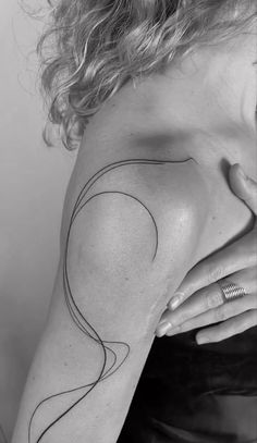 a woman's shoulder with a black and white line drawing on the back of her arm