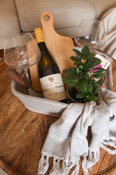 a wooden table topped with a bottle of wine next to a potted plant