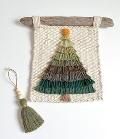 the wall hanging is decorated with multicolored tassels and a wooden stick