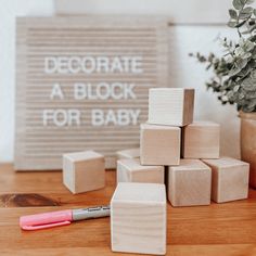 wooden blocks and marker sitting on a table next to a sign that says decorate a block for baby