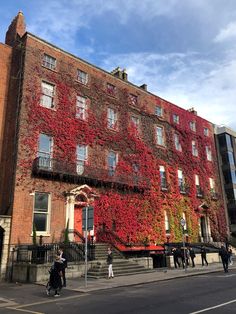 an old brick building covered in red ivys on the side of a city street