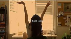 a woman sitting in front of a window with her arms up and the words the final exam written on it