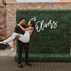 a man holding a woman in front of a sign