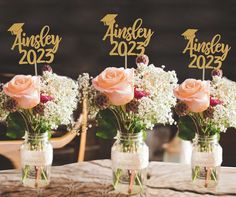 three mason jars filled with pink roses and baby's breath on top of a wooden table