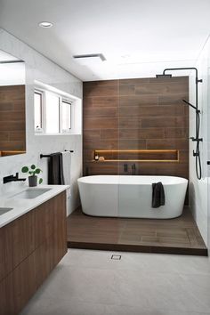 a white bath tub sitting next to a wooden counter top in a bathroom under a window