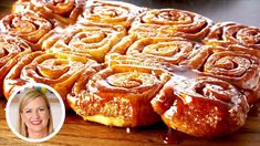 a wooden cutting board topped with lots of doughnuts covered in icing on top of a table