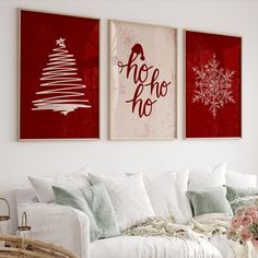 two red and white christmas cards hang on the wall above a couch in a living room