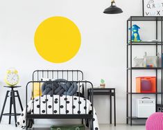 a child's bedroom with a black metal bed and yellow circle wall decal