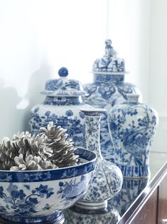 several blue and white vases with pine cones in them