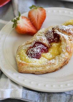 a pastry with powdered sugar and strawberries on it sitting on a white plate