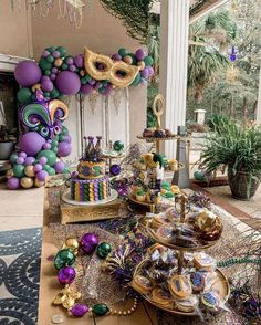 a table filled with lots of different types of desserts and balloons in the shape of mardi gras