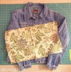 an old jean jacket is laying on top of a cutting mat with the fabric removed