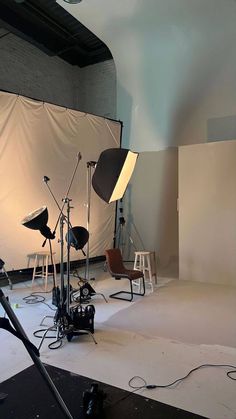 an empty photo studio with several lights and equipment on the floor in front of a white backdrop