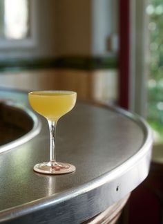 a glass filled with yellow liquid sitting on top of a counter