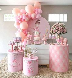 a table topped with lots of pink balloons and cake on top of it's pedestals