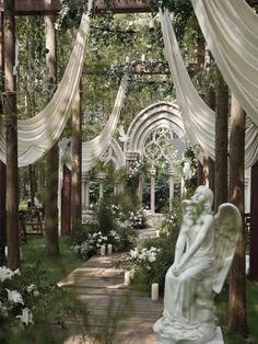 an outdoor garden with white curtains and statues in the foreground, surrounded by greenery