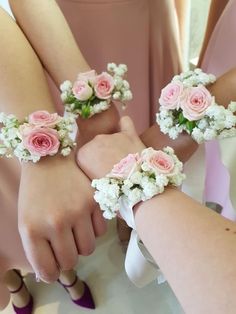 three bridesmaids holding bouquets of pink and white flowers on their wristlets